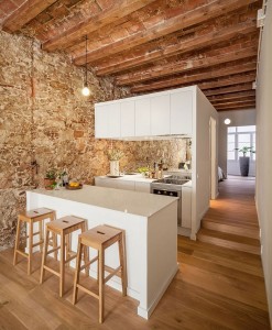 Wooden-ceiling-beams-and-stone-wall-stand-in-contrast-to-the-sleek-white-kitchen